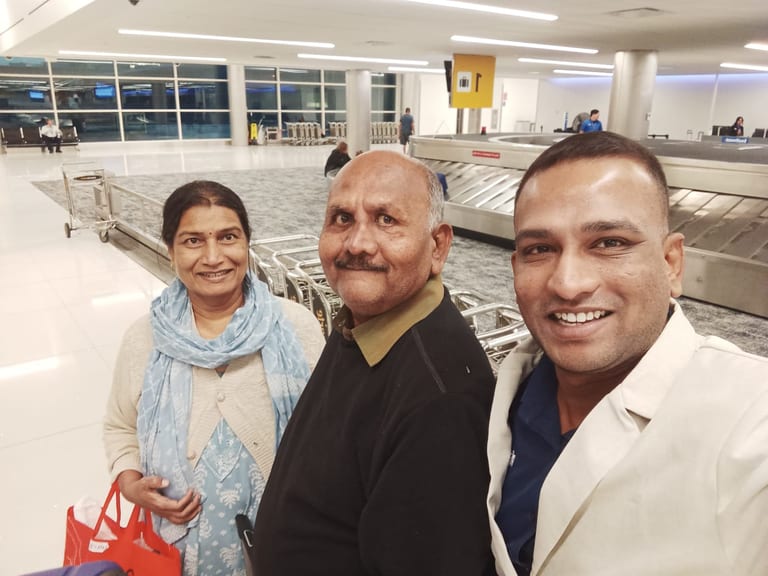 डेन्व्हर विमानतळावर बॅगेज बेल्टजवळ सुजीत, बाबा आणि आई यांचा आनंदी सेल्फी